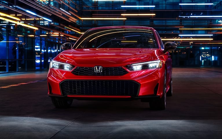 2027 Honda Civic Sedan Sport Touring Hybrid in Rallye Red front view with headlights on (Compact Sedan)